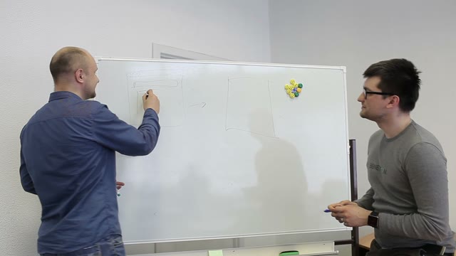 Two Man Draw Diagrams On The White Board And Discuss