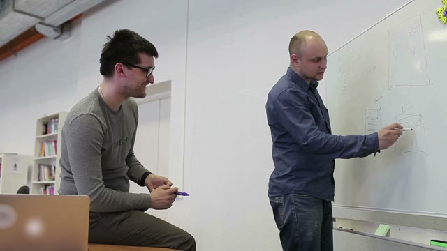 Two Man Draw Diagrams On The White Board And Discuss