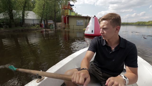 Man In The Boat Rowing On The Pond.