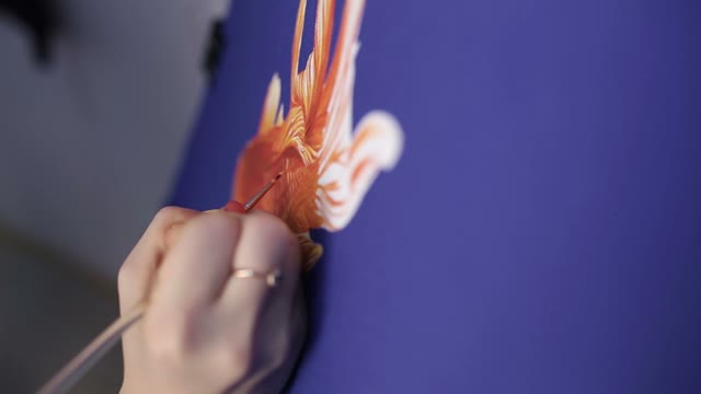 The Hand Of A Girl With A Brush. Draws A Fish