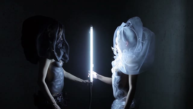 Two Models In Black And White Standing Next To The Lamp In The Dark