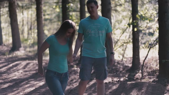 A Smiling Couple Walking Along A Forest