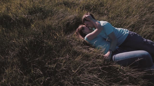 Happy Couple Lying On The Grass And Kissing