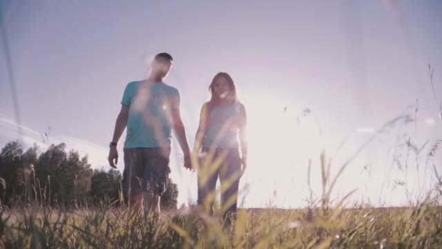 Couple Holding Hands And Walking On The Grass In A Meadow