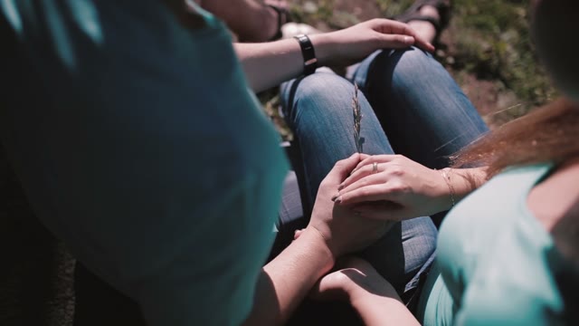 Lovers Sit On Nature. Close-up Of Holding Hands