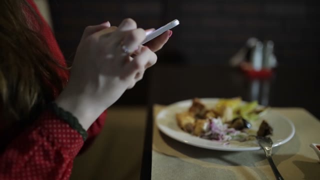 Beautiful Girl Looking In The Smartphone In The Restaurant. Close-up.