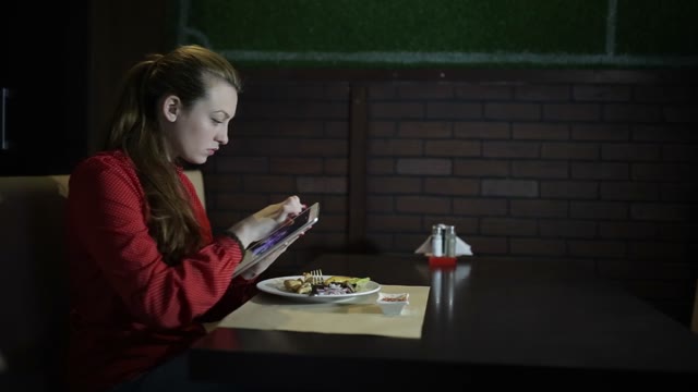 Beautiful Girl In Red Dress Working With The Tablet For A Cafe Table. Close-up