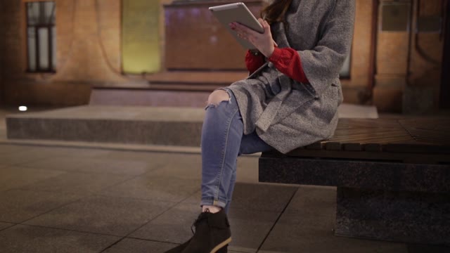 Beautiful Woman In A Coat With A Clipboard On A Bench In The Evening.