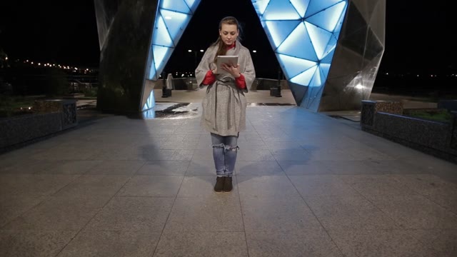 The Girl With The Tablet On The Street On A Background Of Glowing Arches.
