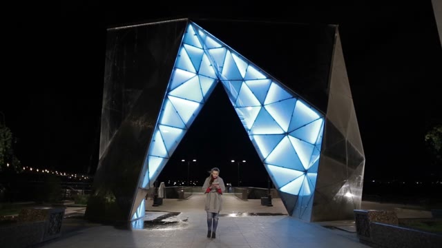 Girl Walking Down The Street With A Tablet In The Evening.