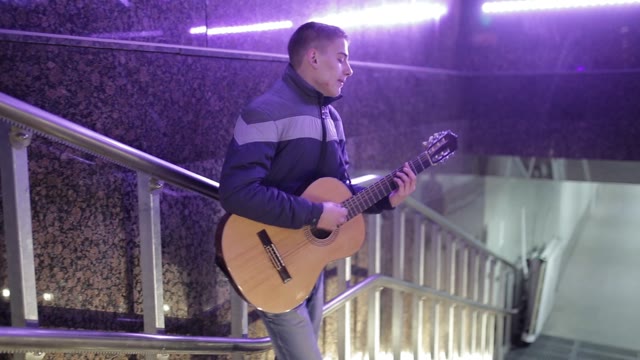 A Young Man Plays Guitar And Sings In The Underground Crossing.