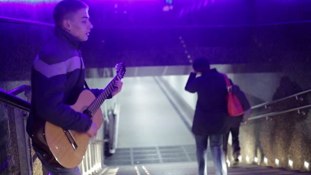 A Young Man Plays Guitar And Sings In The Underpass.