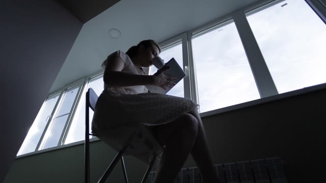 Girl With Tablet Sitting On The Balcony At The Window And Drink Of The Cup