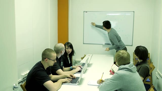 Lecturer Explains Something To A Small Group With A Laptop And Draws On The