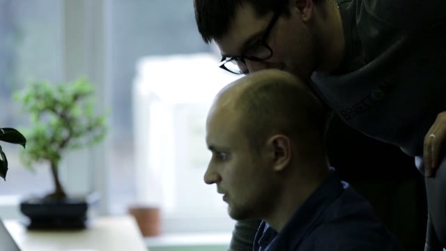 Two Men Look At A Monitor And Discussing Something