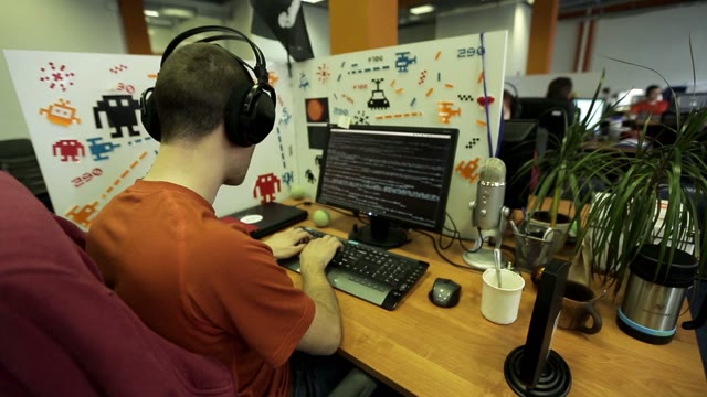 Programmer In Headphones Sitting At The Computer