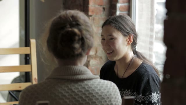 Two Girls In A Cafe Smiling And Drinking Coffee