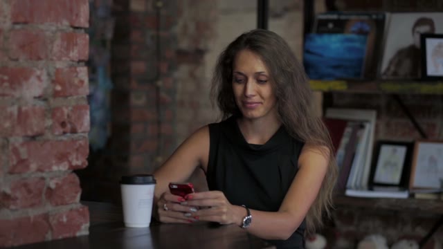 A Woman With A Phone In A Cafe Smiling