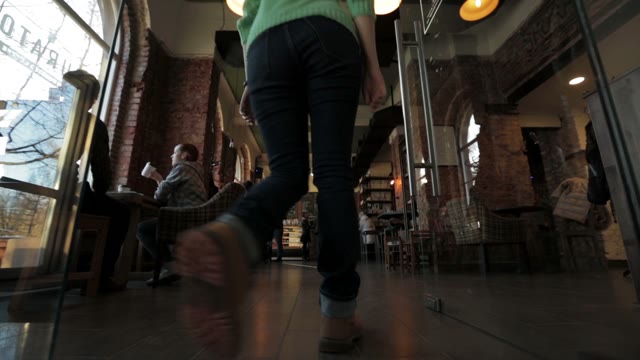 A Young Girl Goes To The Cafe. The Camera Shoots From The Bottom