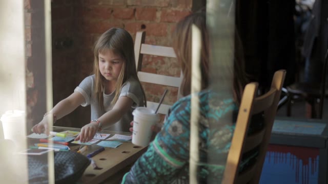 Little Girl Draws Markers At A Table In A Cafe
