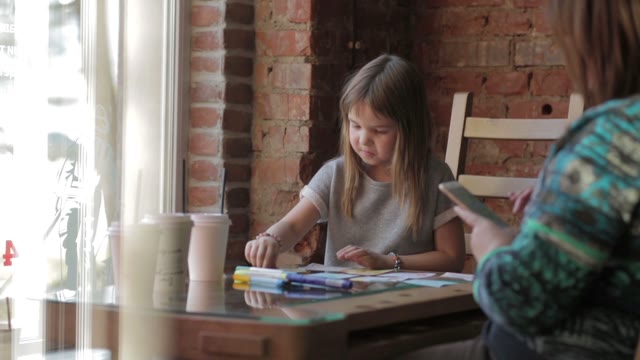 Girl Draws And Smiling In A Restaurant