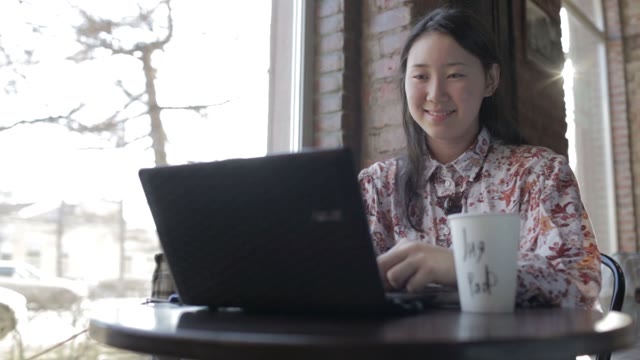 Young Asian Smiling With A Laptop In A Cafe