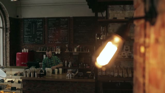 Close Up Of A Lamp Turned Off In A Cafe. The Staff Behind The Bar In The