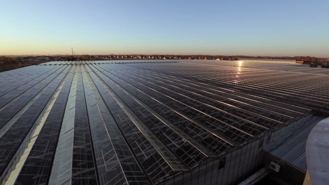 Large Industrial Building With A Glass Angled Roof Reflecting The Sun's Rays