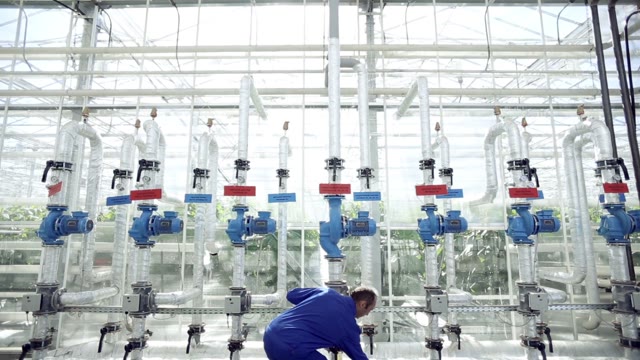 Technician Repairing The Heating System In The Greenhouse