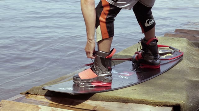 Young Man Tying On His Feet For Wakeboard.