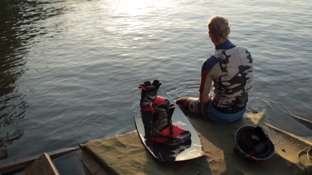 Wakeboarder Resting After A Workout On The Pier.
