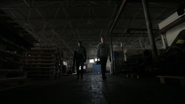 Two Men Go On Camera With A Tool, Leaving The Warehouse.