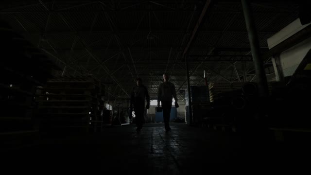 Two Young Men With The Tools To The Camera In A Dark Hangar