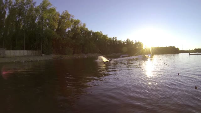 At Sunset, A Man Does Tricks On A Wakeboard. Slow Motion