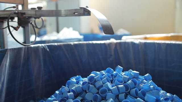 Many Blue Plastic Bottle Caps Fall From Conveyor To The Box.