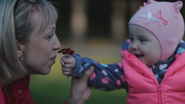 Funny Child Gives Her Mother To Smell A Flower.