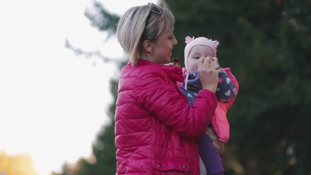 Mother Holds Child On Hands On A Background Of Forest.