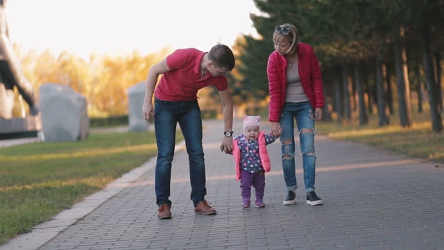 Happy Family Goes On A Park Alley.