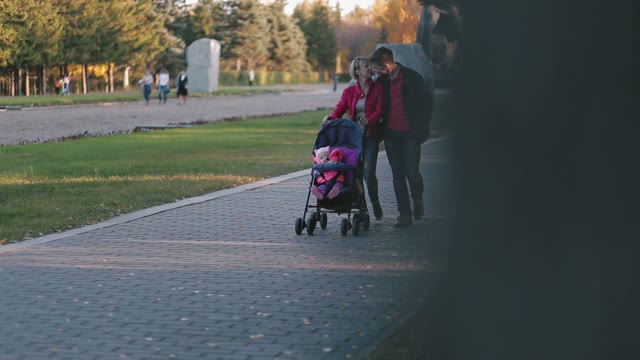 Happy Family Walks With The Child In A Baby Carriage In The Autumn Park.