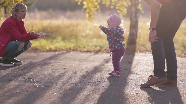 In Autumn Park Child Takes Its First Steps With His Family.