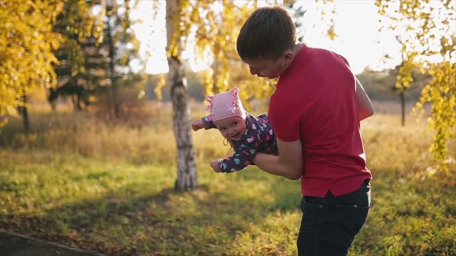 Father Turns The Child In His Arms In Autumn Park.