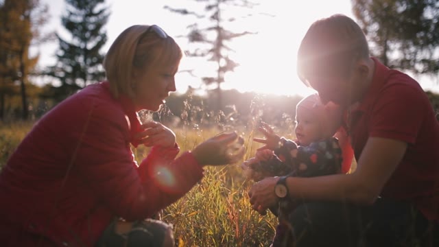 Parents Talk To The Baby In The Autumn Field.