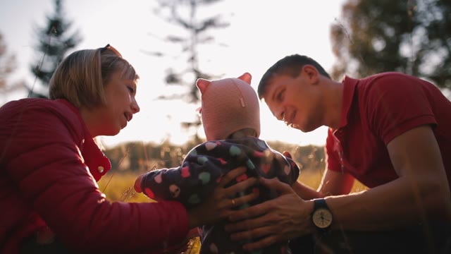 Happy Parents Talk With The Baby In The Autumn Field.