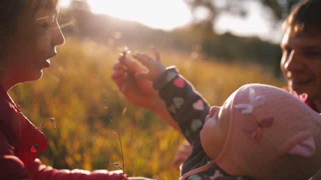 Happy Parents With Baby On Autumn Field.