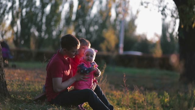 Happy Family With Child On Autumn Field. Beautiful Sun Shines.