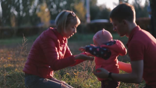 Happy Family Playing With Daughter In The Autumn Field. Mother Kissing Baby.