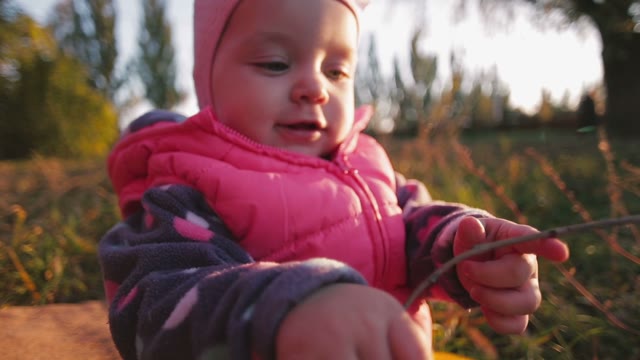 Little Girl In The Autumn Meadow Holding A Twig And Twists It.