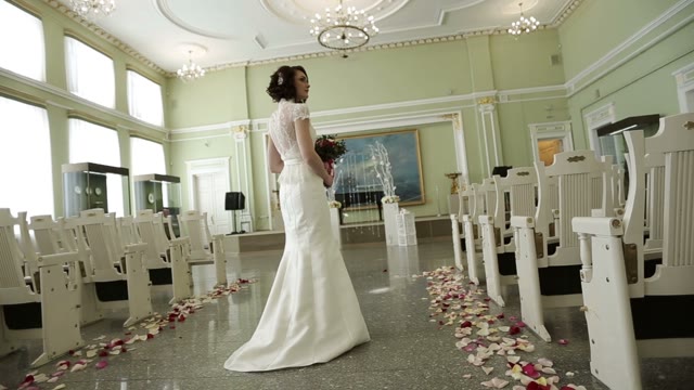 Bride With Bouquet Of Flowers Standing In The Middle Of The Hall.