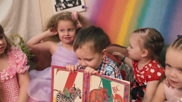 Boy Holding Alphabet, Girls Sit Around.