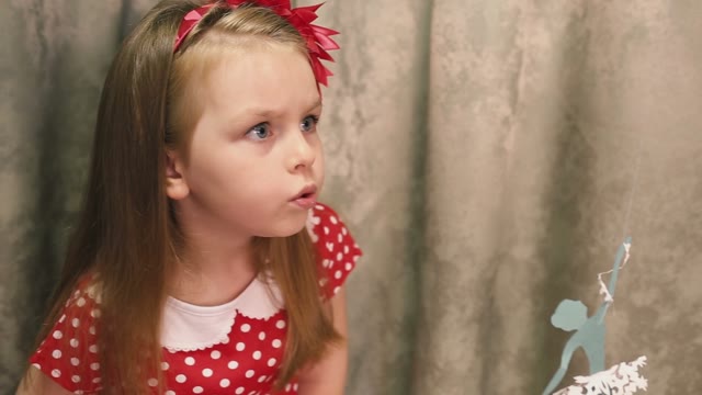 Girl In Red Blowing A Paper Ballerina.